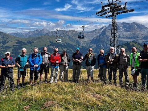 Gruppe von Wanderern vor Bergkulisse und Seilbahn in den Alpen.