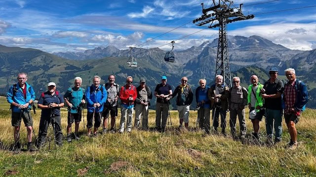 Gruppe von Wanderern vor Bergkulisse und Seilbahn in den Alpen.